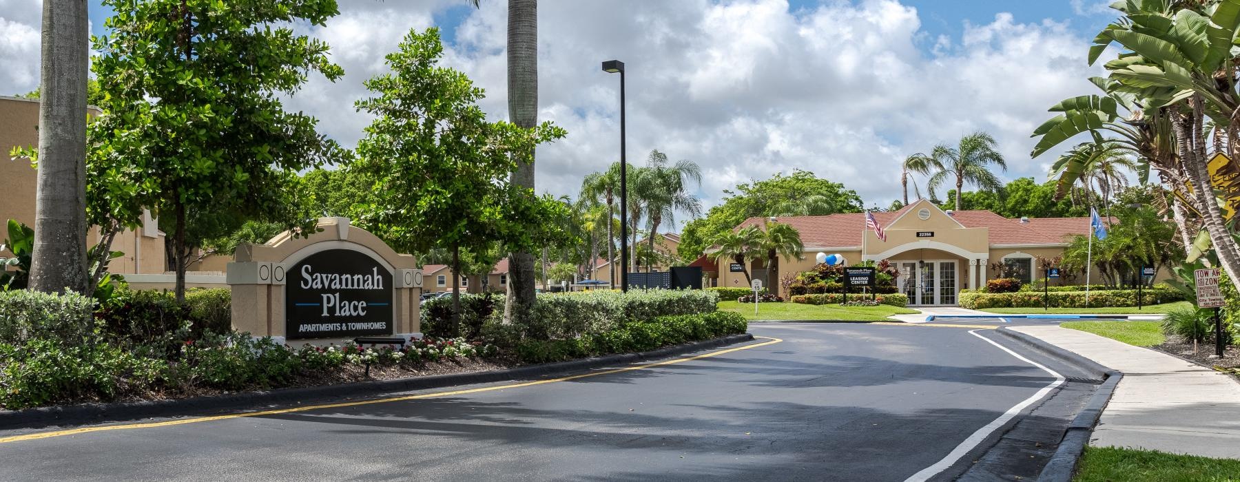 a street with palm trees and a sign on it